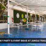 Birthday Party & Event Ideas at Jungle Trail Noida,” showing an outdoor restaurant seating area with white tables, a covered canopy, greenery wall decor, and blue tiled flooring.