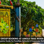 Jungle Trail Noida promotional banner featuring an “Australia” themed sign with animal illustrations, greenery, and a safari-style vehicle on a pathway, with city buildings in the background.